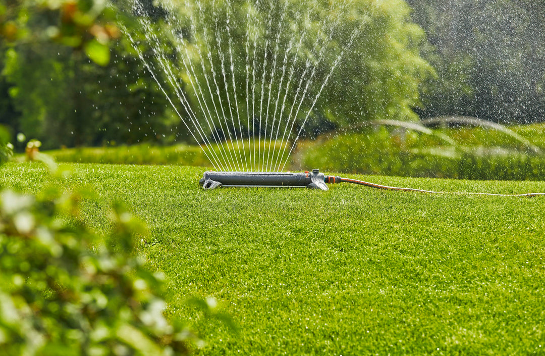 Oscillating sprinkler creating fine mist over green grass