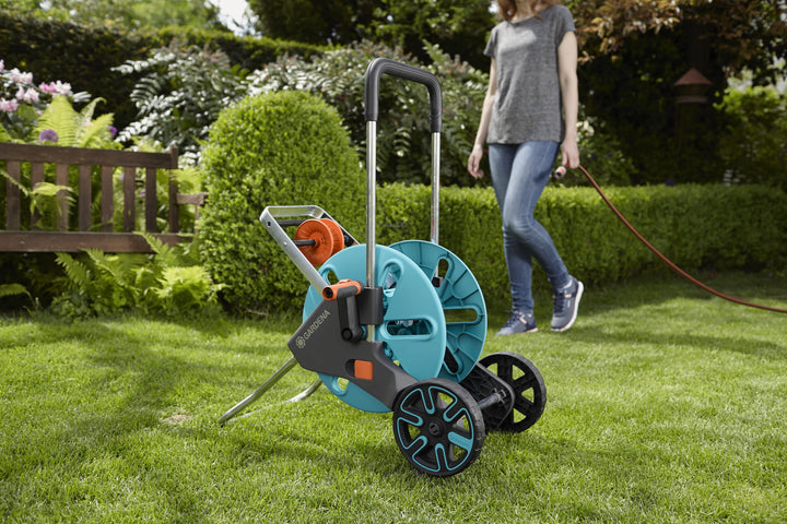 Hose trolley on lawn with aqua reel, black cart frame and large blue wheels