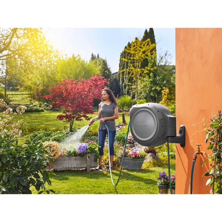 Outdoor retractable hose reel on wall with blue hose connected for watering