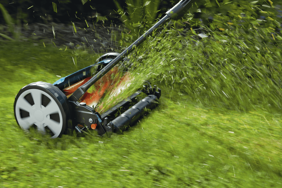 Blue and black cylinder lawnmower cutting grass with orange underside blades.