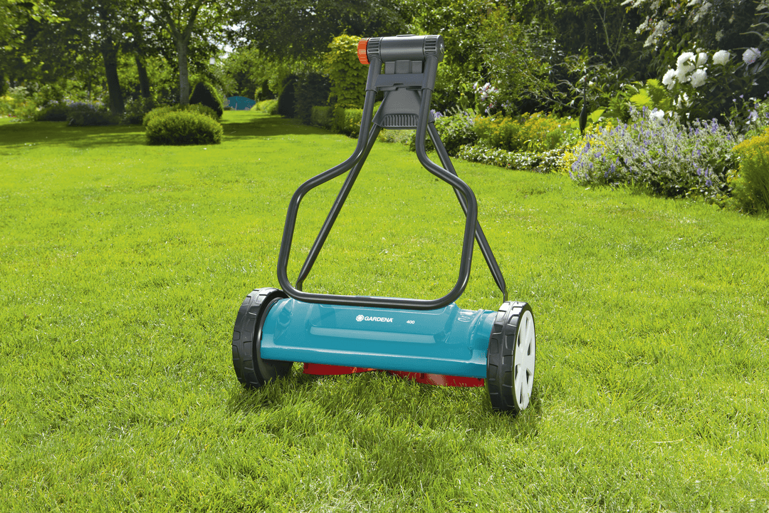 Teal and gray cylinder lawnmower with tall handle and front roller wheels.