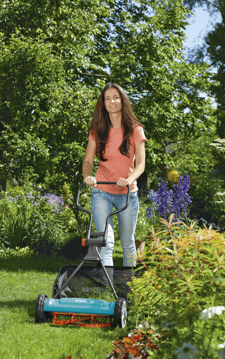 Black grass catcher bag attached to a lawn mower while mowing on grass.