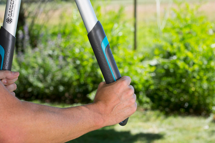 Pruning lopper close-up held by silver handle with black-and-blue grip and orange latch
