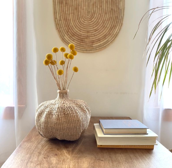 Woven basket with rounded belly and narrow neck, tan natural fiber on tabletop