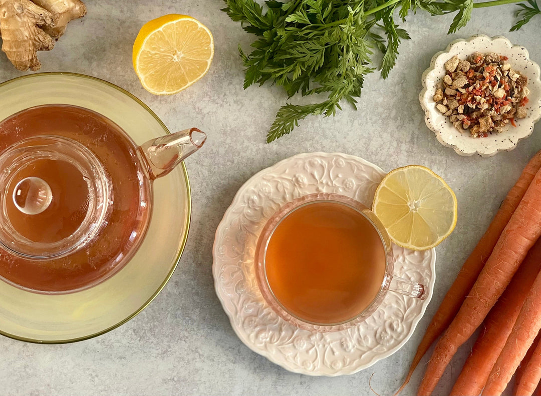 Amber ginger tea in clear cups, with lemon slices and carrots on a platter