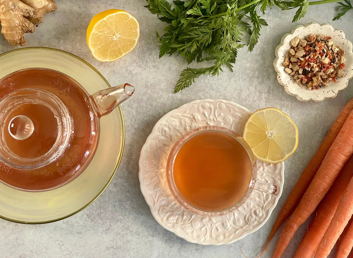 Amber ginger tea in clear cups, with lemon slices and carrots on a platter