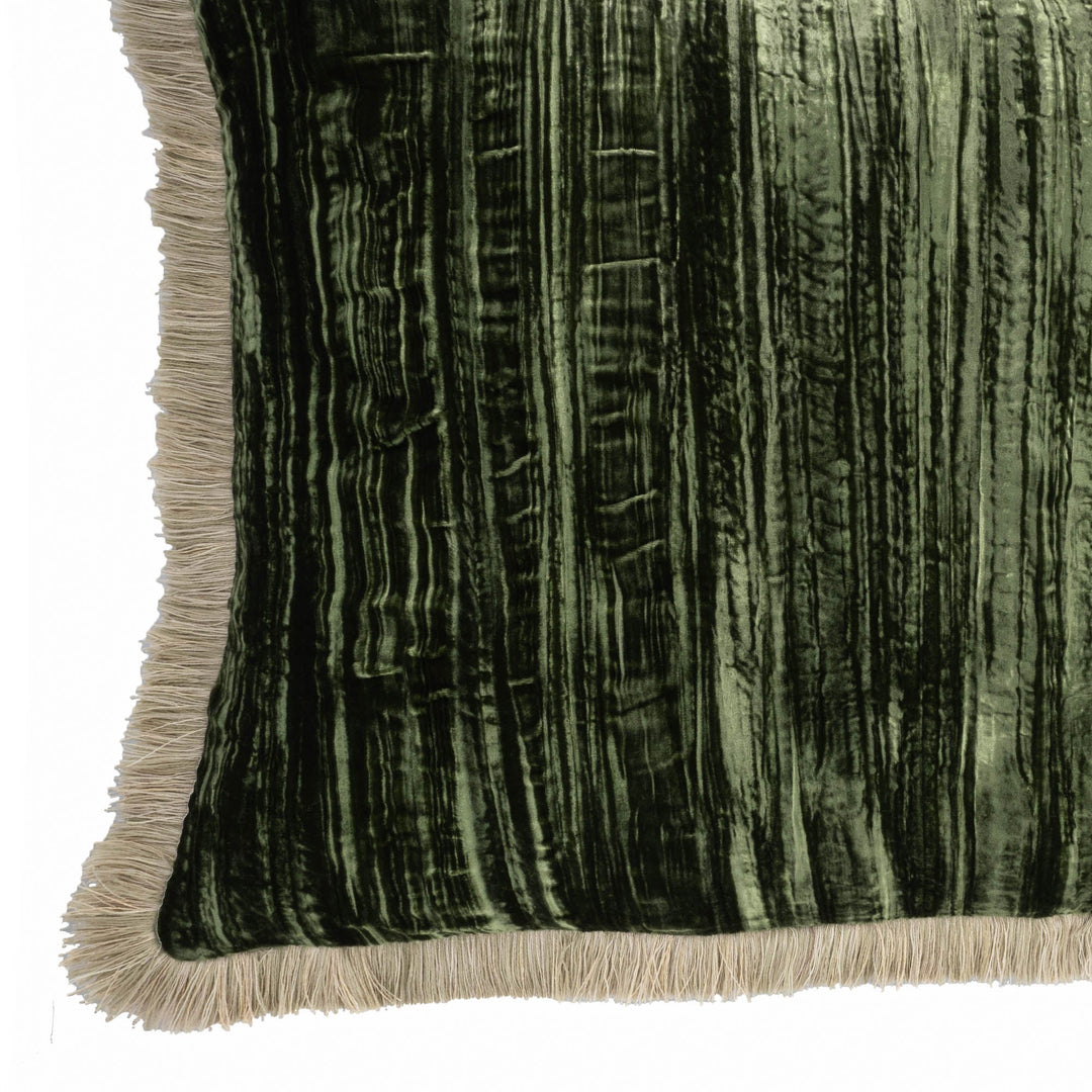Green velvet pillow side with beige fringe along bottom edge, textured vertical pattern.