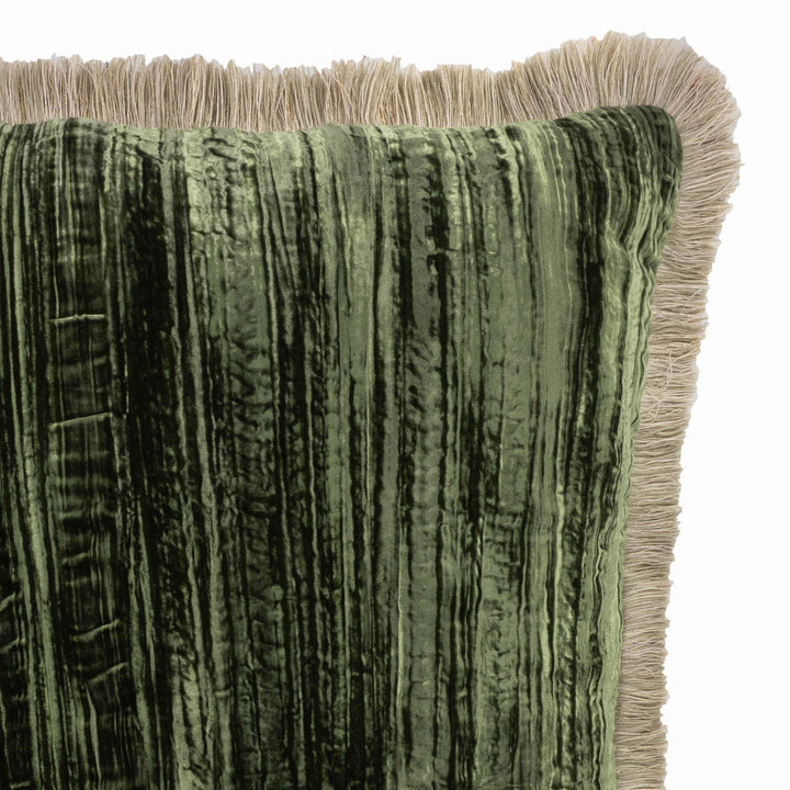 Close-up of green velvet pillow front with vertical texture and beige fringe border.