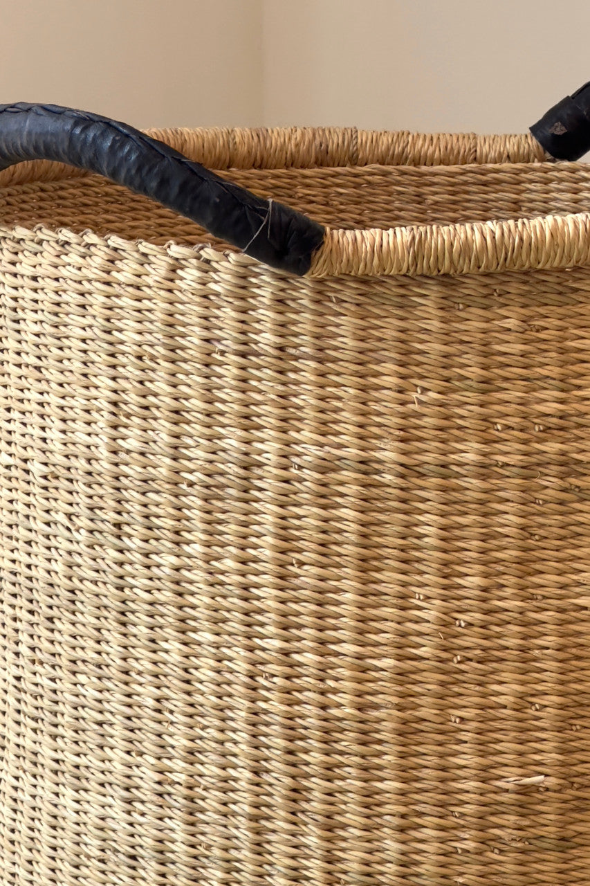 Woven basket weave detail with black fabric handles on tan rim