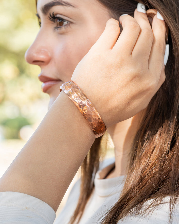 Hammered copper cuff bracelet on wrist, wide band with textured hammered finish