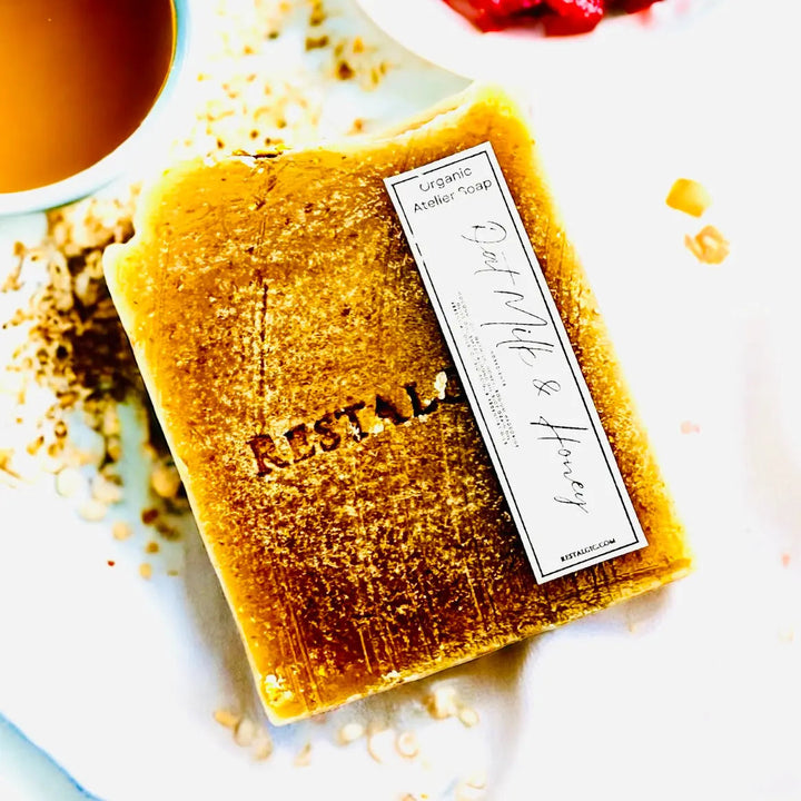 Gold handcrafted natural soap bar with organic Atelier Soap label and dusting.