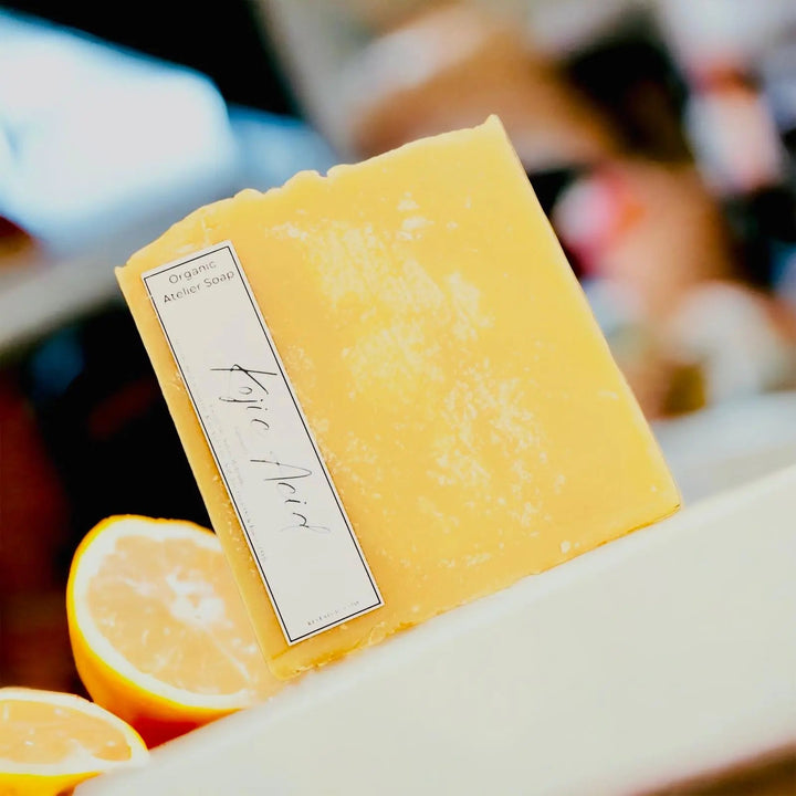 Bright yellow handcrafted natural soap bar with organic Atelier Soap label.