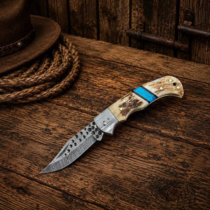 Antler and turquoise folding pocket knife with damascus blade on wooden surface