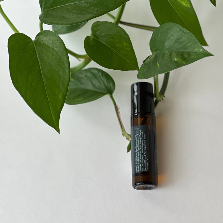 Botanical perfume oil bottle with black cap, label visible, amber liquid