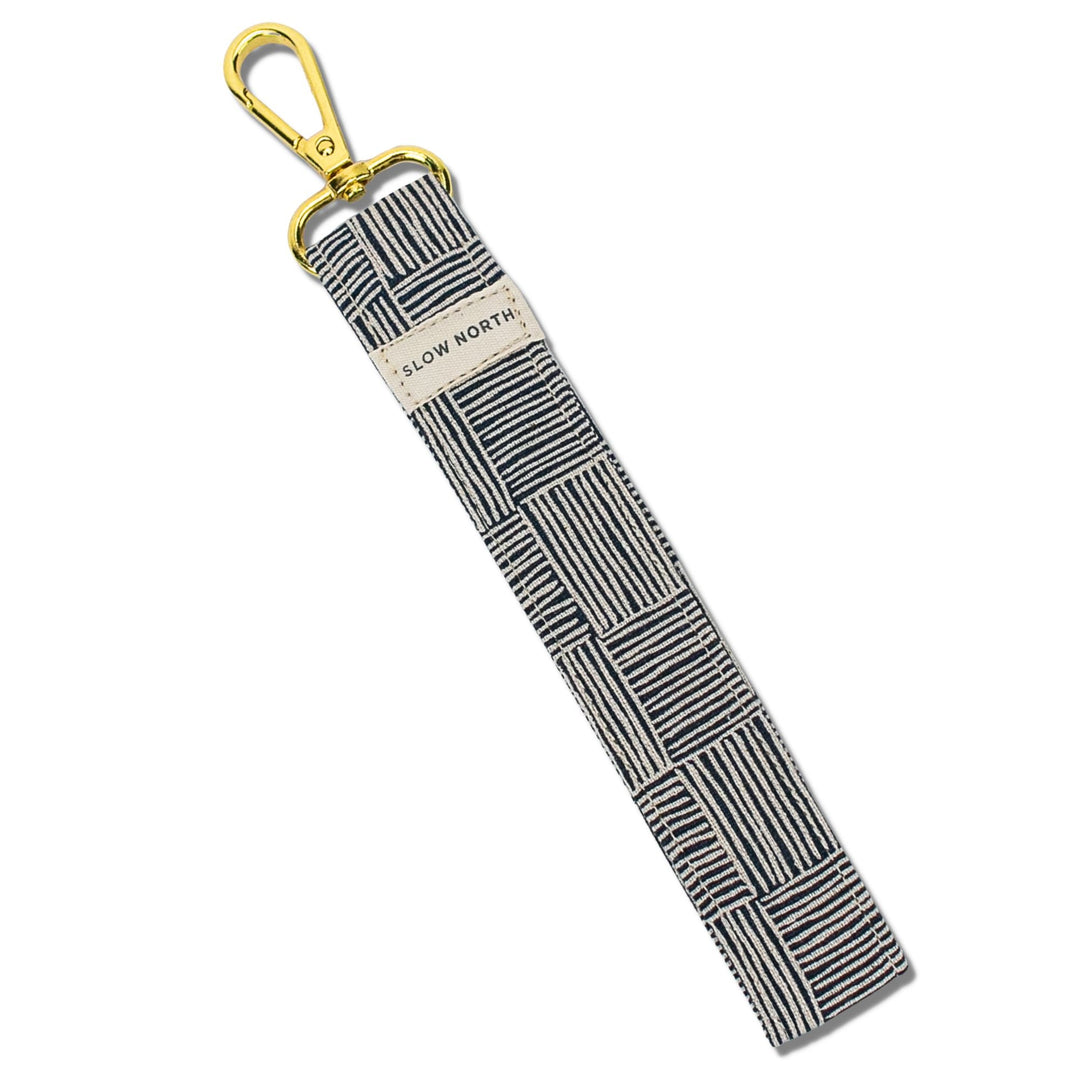 Wristlet keychain with striped fabric band, gold key ring, and “SLOW NORTH” label