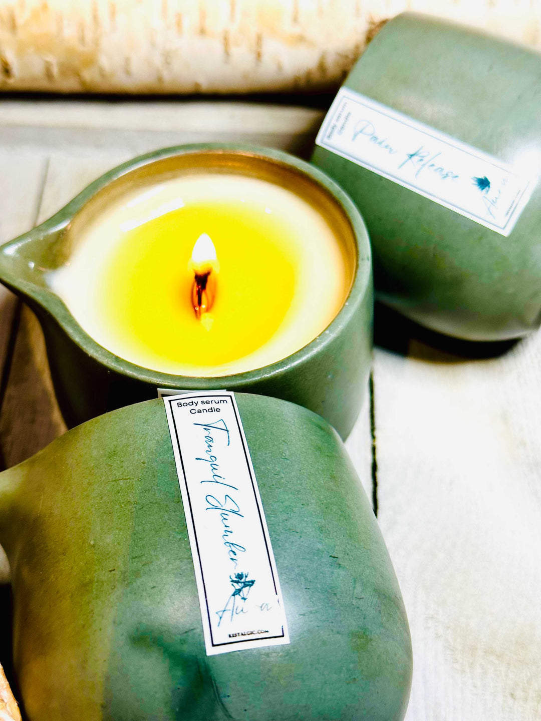Green ceramic candle cup with warm flame and a labeled body serum container