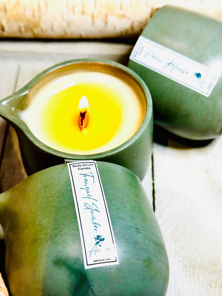 Green ceramic candle cup with warm flame and a labeled body serum container