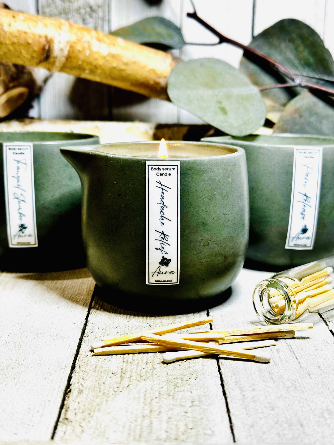 Green ceramic candle and body serum tub with roller sticks on a tabletop