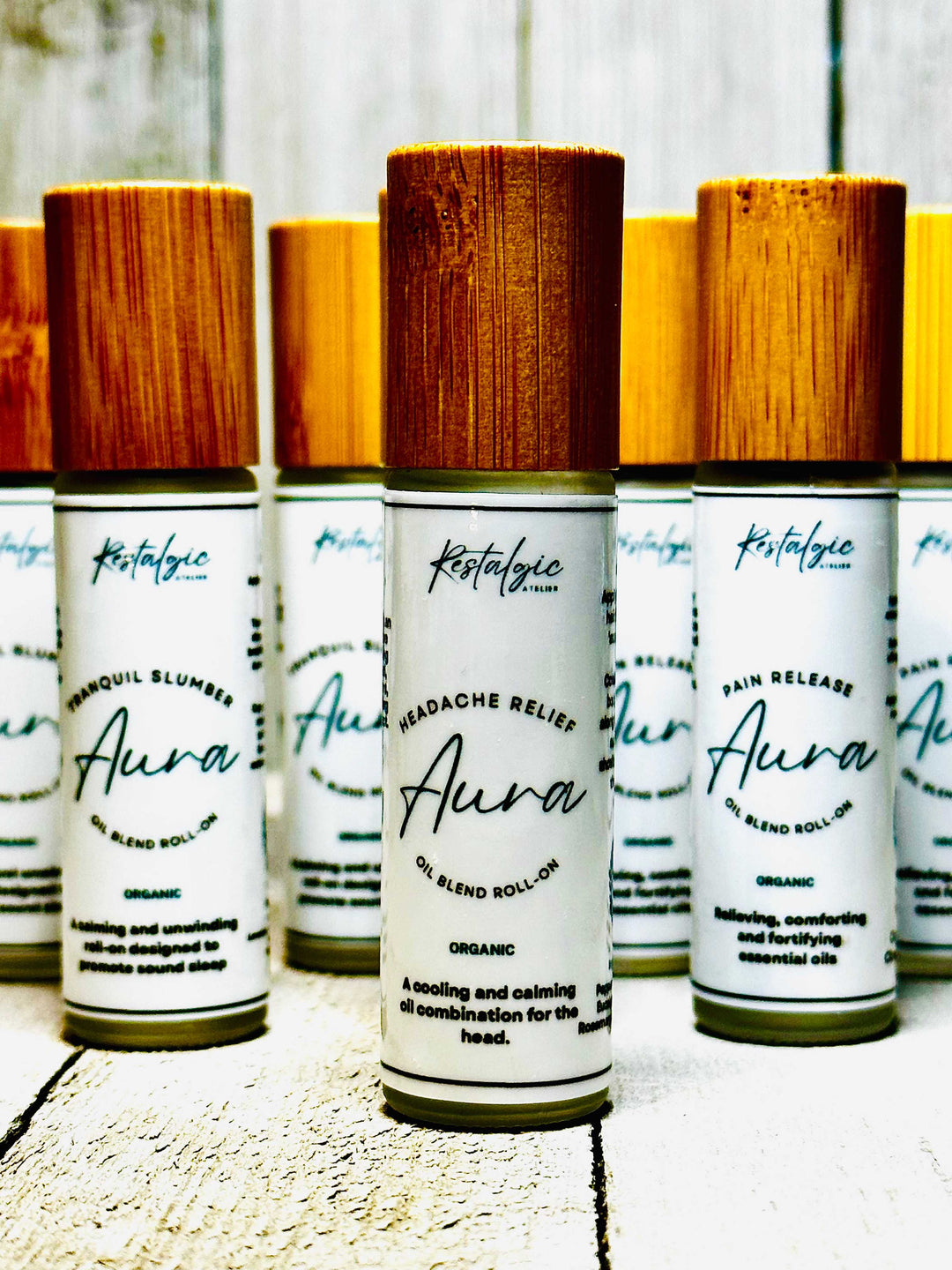Set of Aura headache relief blend roll-on bottles with wooden caps in a row