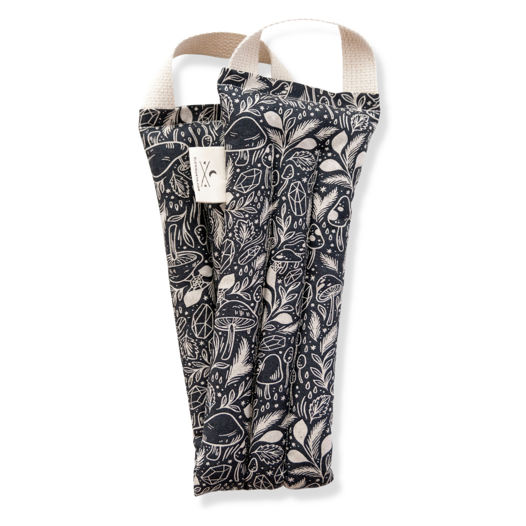 Black and white patterned neck wrap with cream handle straps and woven fabric pouch