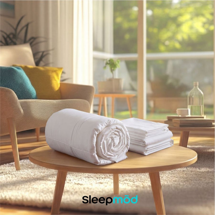 White cooling comforter and pillow shams, neatly folded into a rolled bundle