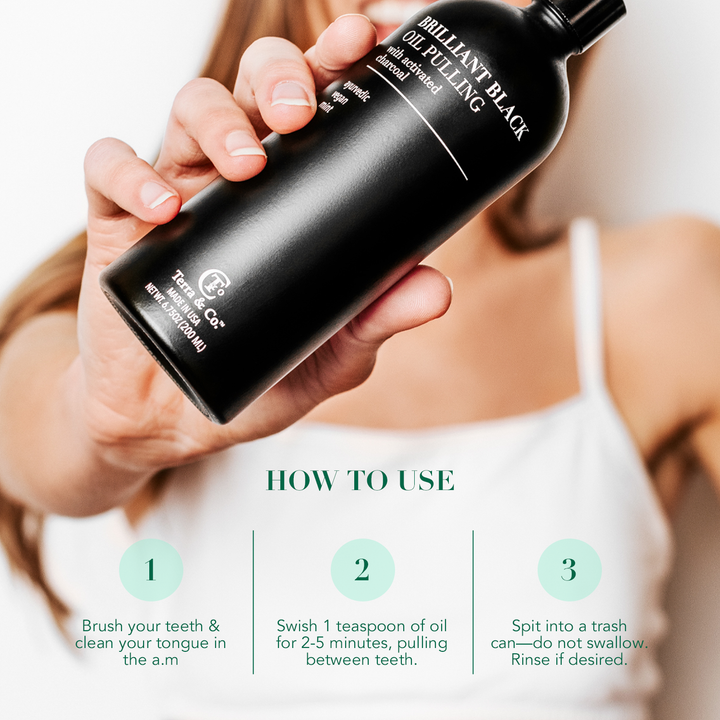 Hands holding a Brilliant Black oil pulling charcoal mouthwash bottle