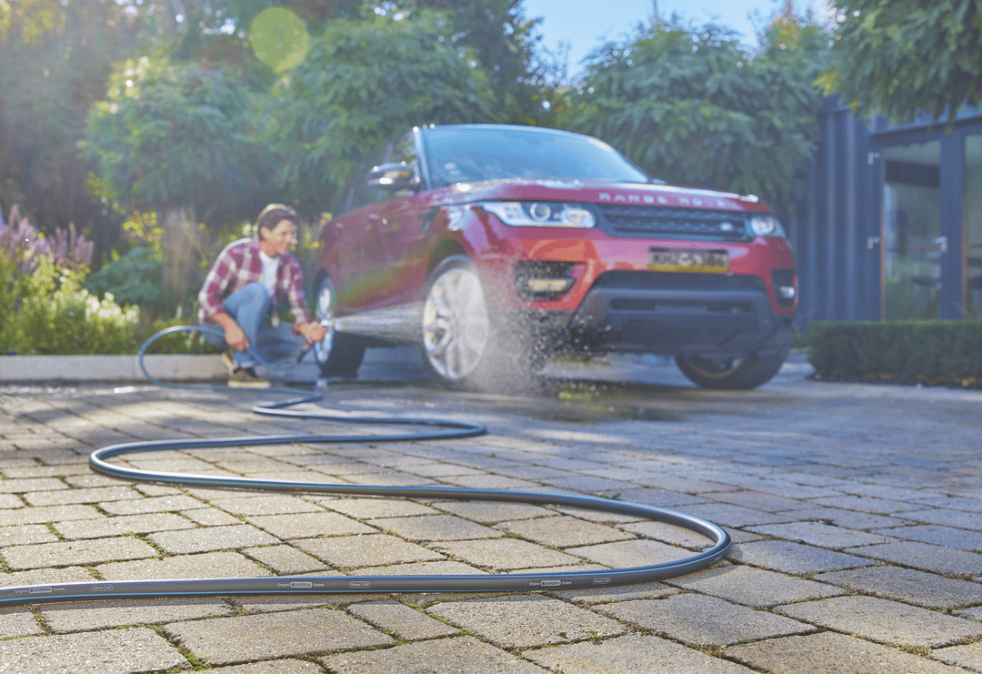 Garden hose laid out in a straight line across a paved walkway