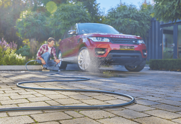 Garden hose laid out in a straight line across a paved walkway
