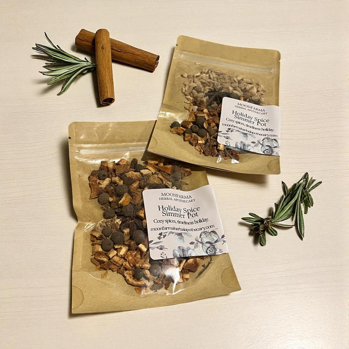 Three kraft simmer pot pouches with white labels, dried botanicals with rosemary and sticks.
