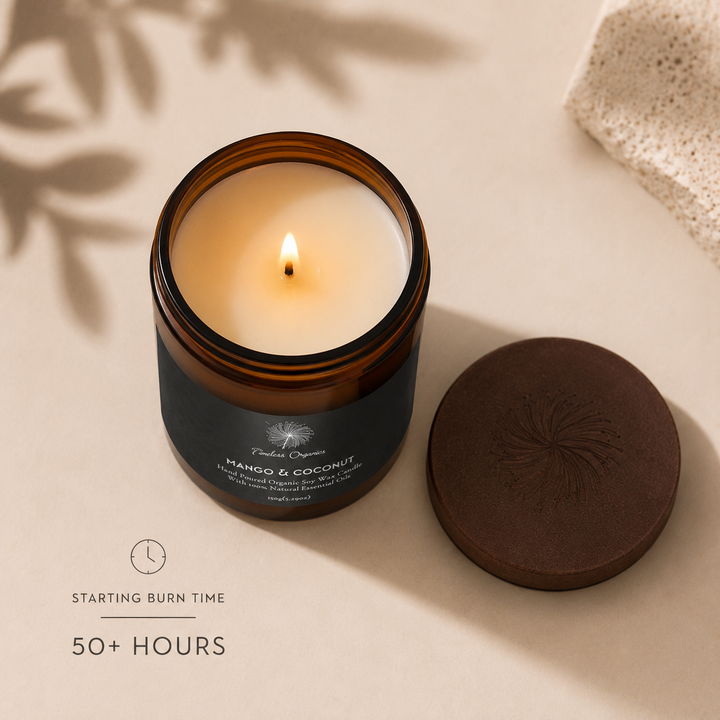 Lit Mango &amp; Coconut candle in amber glass jar with black label and lid