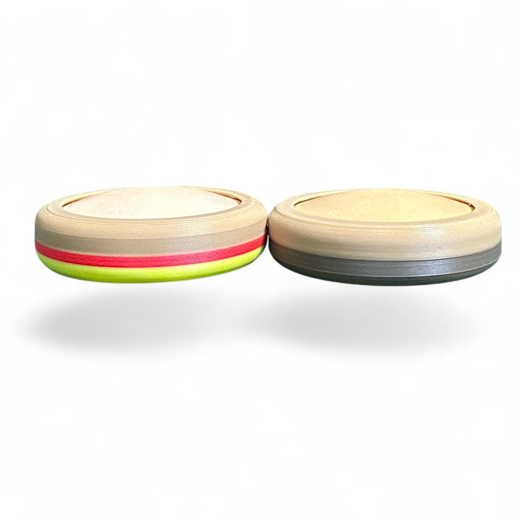 Two small round striped toy pieces, tan with red and green accents