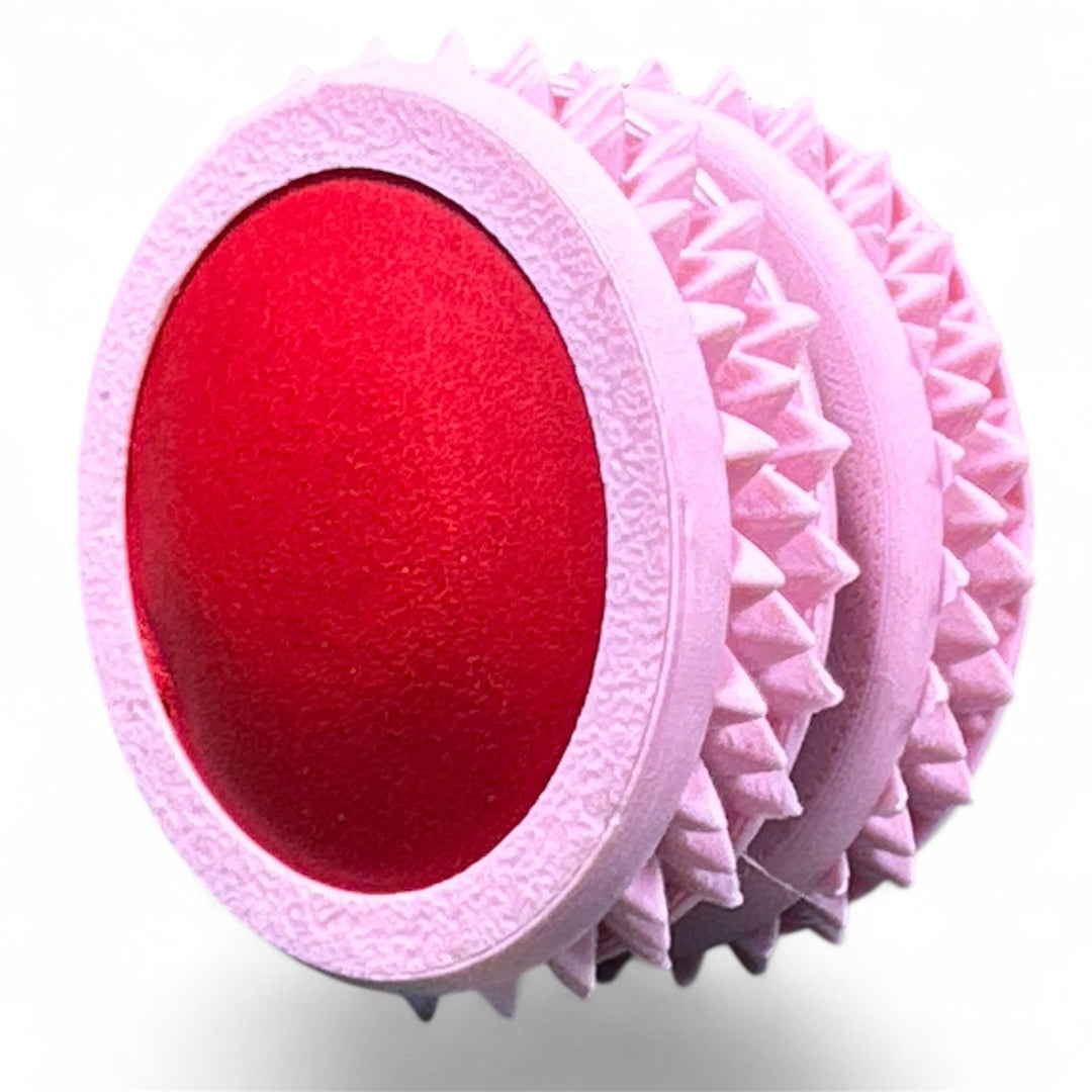 Pink fidget moon toy with red oval center and ridged spiky edges