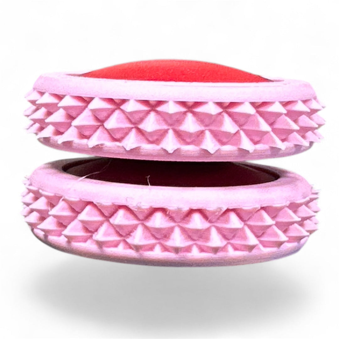 Pink fidget moon toy with layered ridged ring and red inner oval