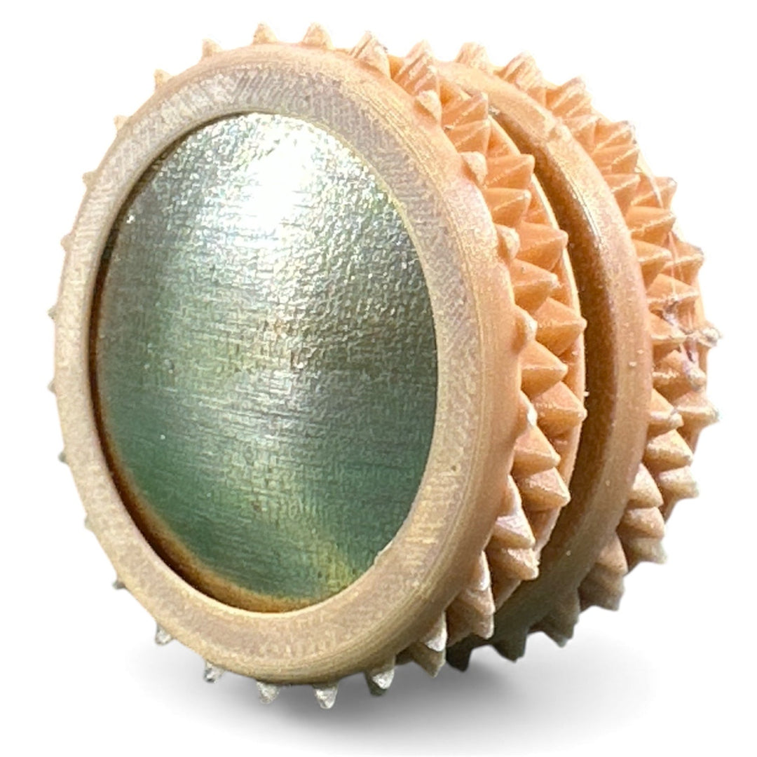 Tan fidget moon toy with textured green oval center and spiky ring