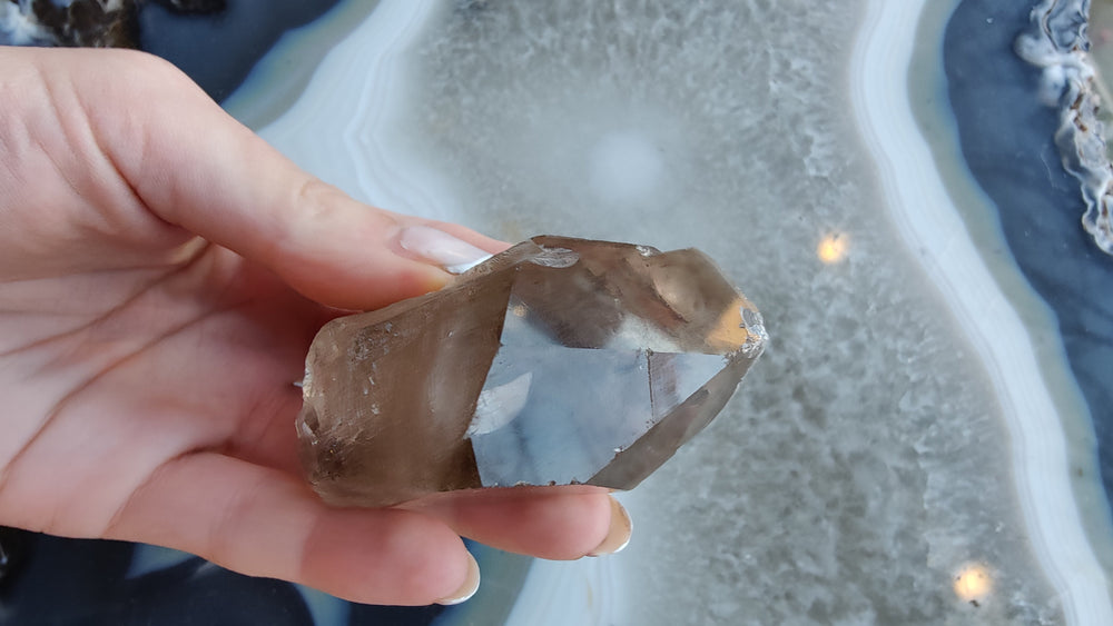 Smoky quartz crystal specimen with smoky brown and translucent light facets, held up close.