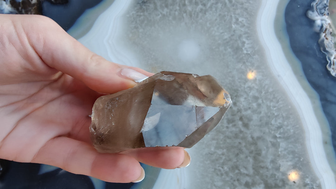 Smoky quartz crystal specimen with smoky brown and translucent light facets, held up close.