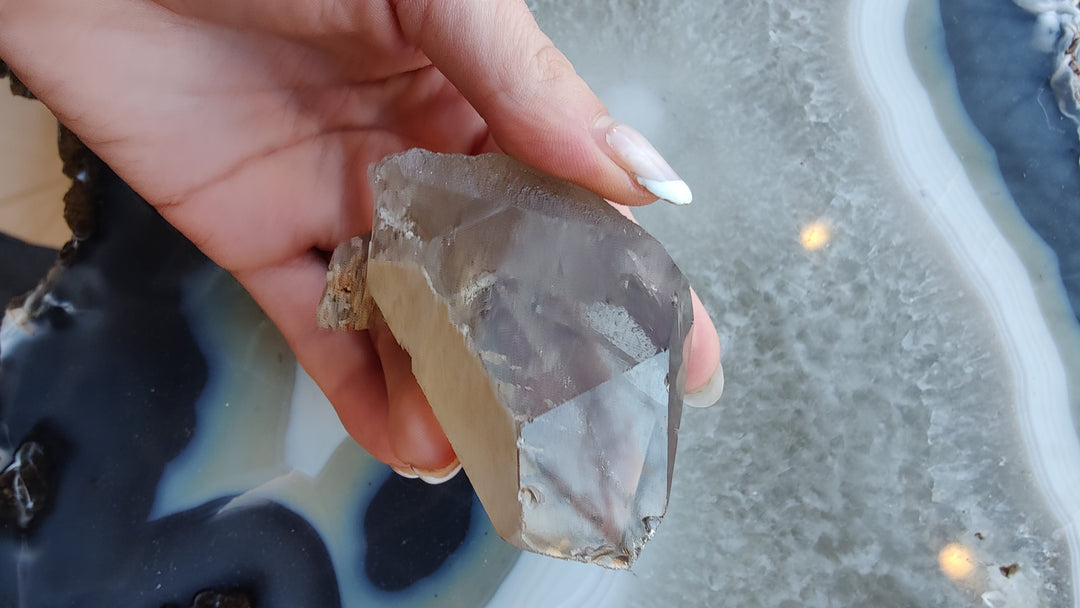 Smoky quartz crystal with angular cut faces and smoky brown tones, shown in hand.