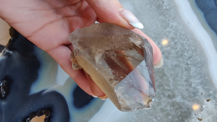 Smoky quartz crystal chunk with smoky brown top and translucent edge facets, hand-held.