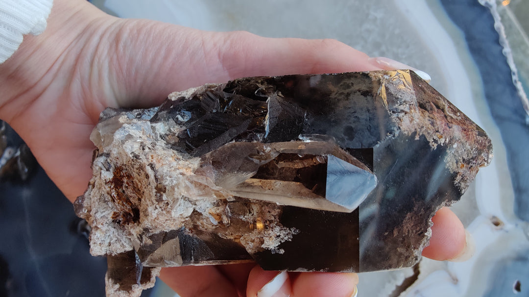 Smoky quartz point with dark smoky crystal facets on rough stone base