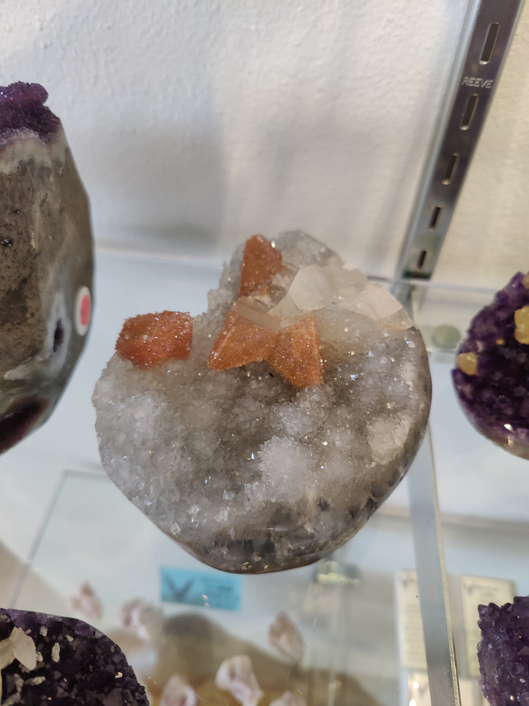 Round geode sculpture with crystal druzy and orange quartz-coated calcite inclusions