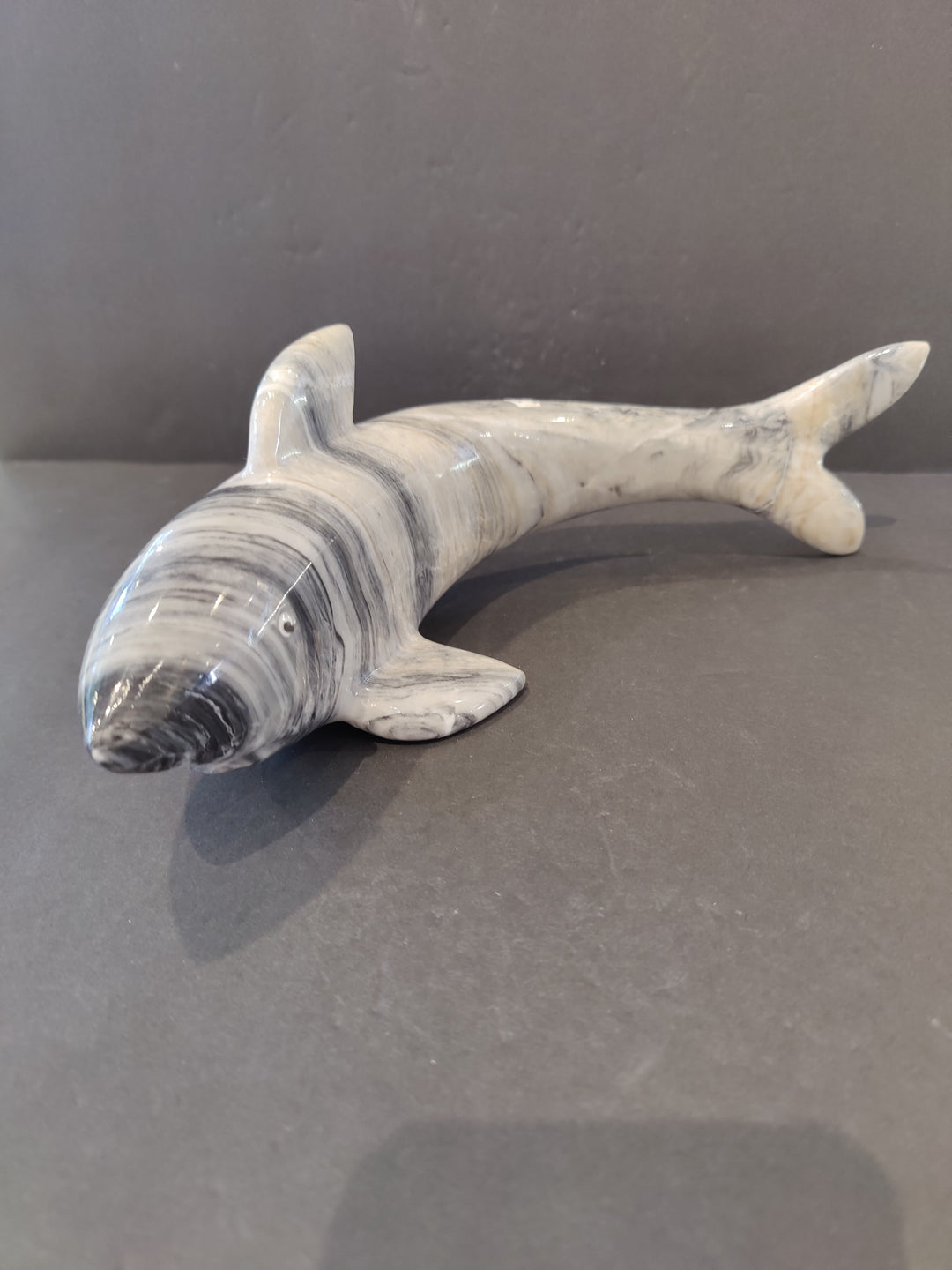 Carved shark sculpture, light gray stone with spiral belly details and open-mouth shape