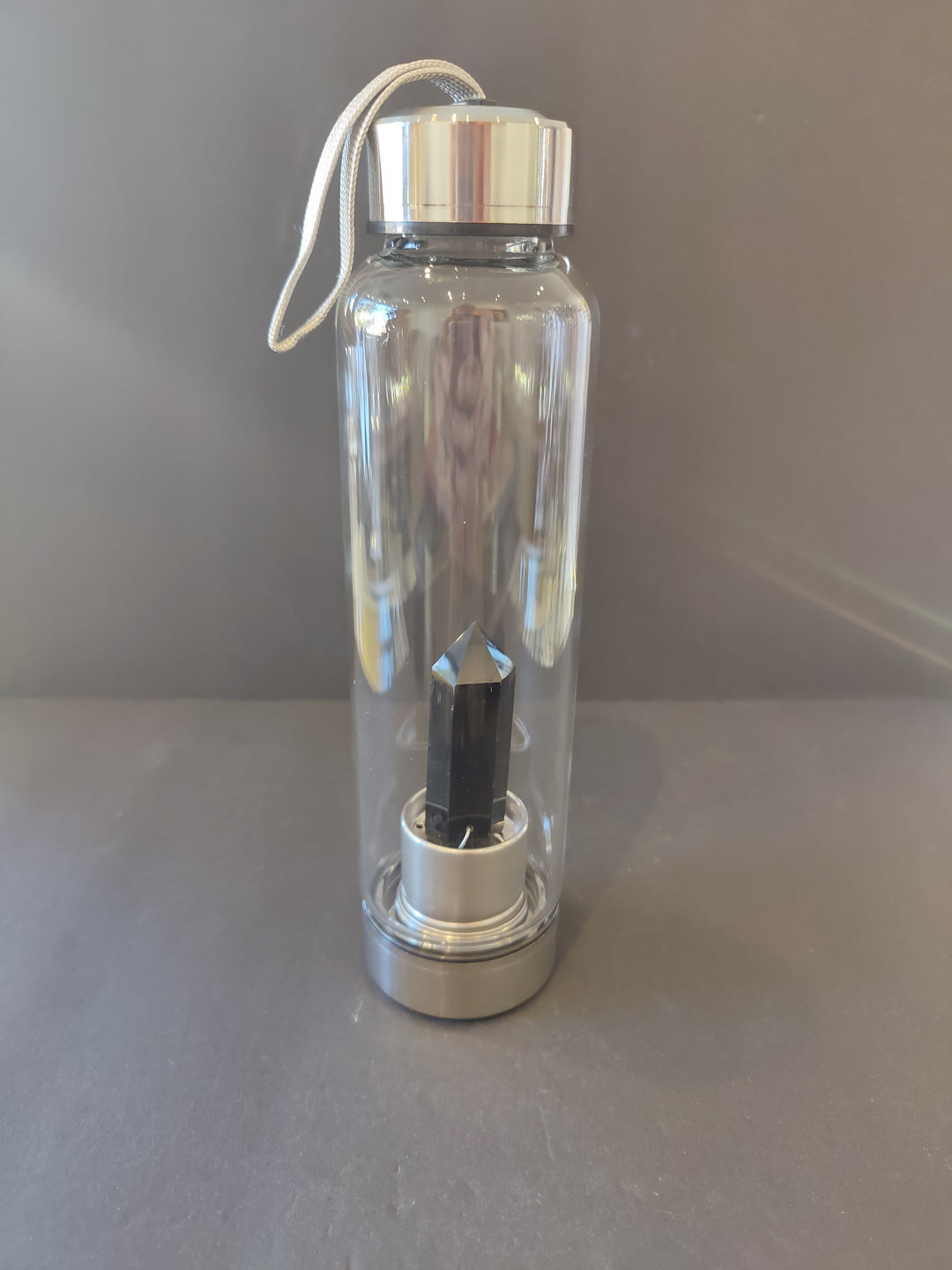 Crystal-infused glass water bottle with stainless steel cap and dark crystal insert