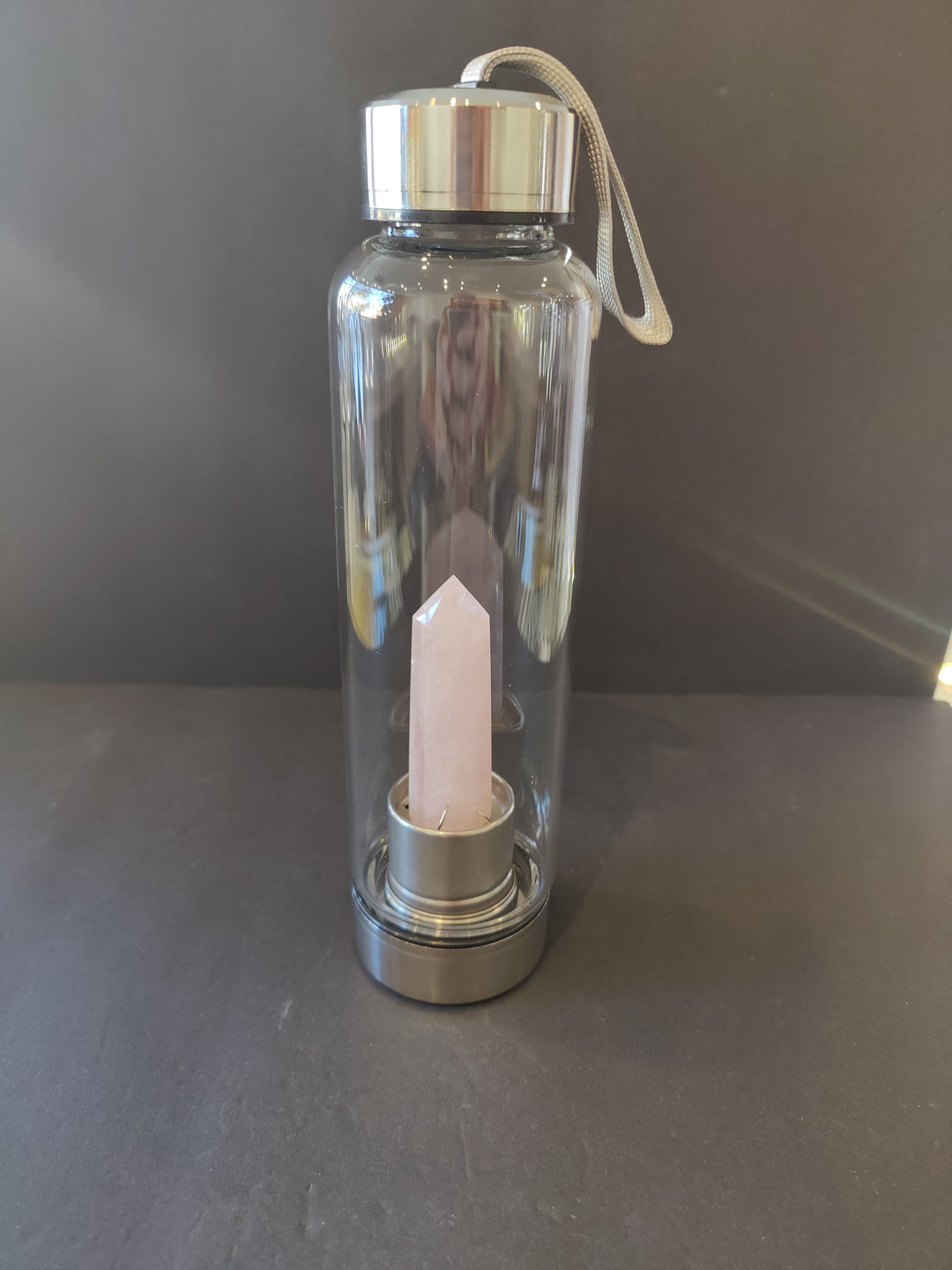 Crystal-infused glass water bottle with stainless steel cap and tall white quartz insert