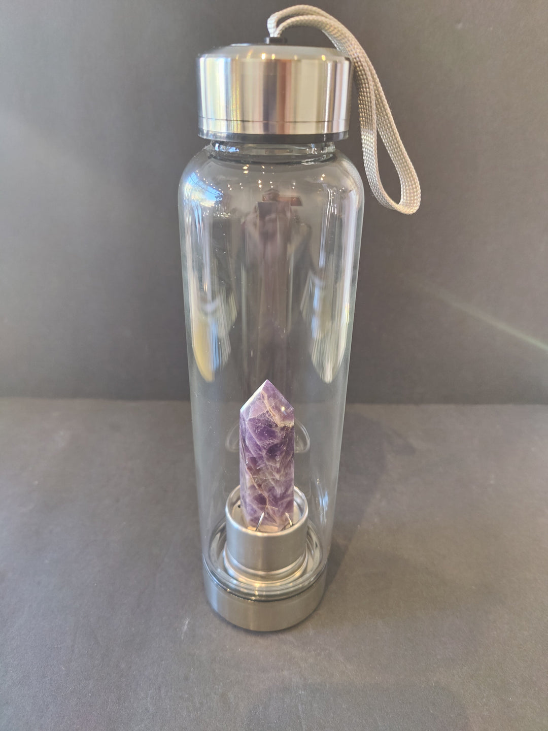Crystal-infused glass water bottle with stainless steel cap and purple crystal insert