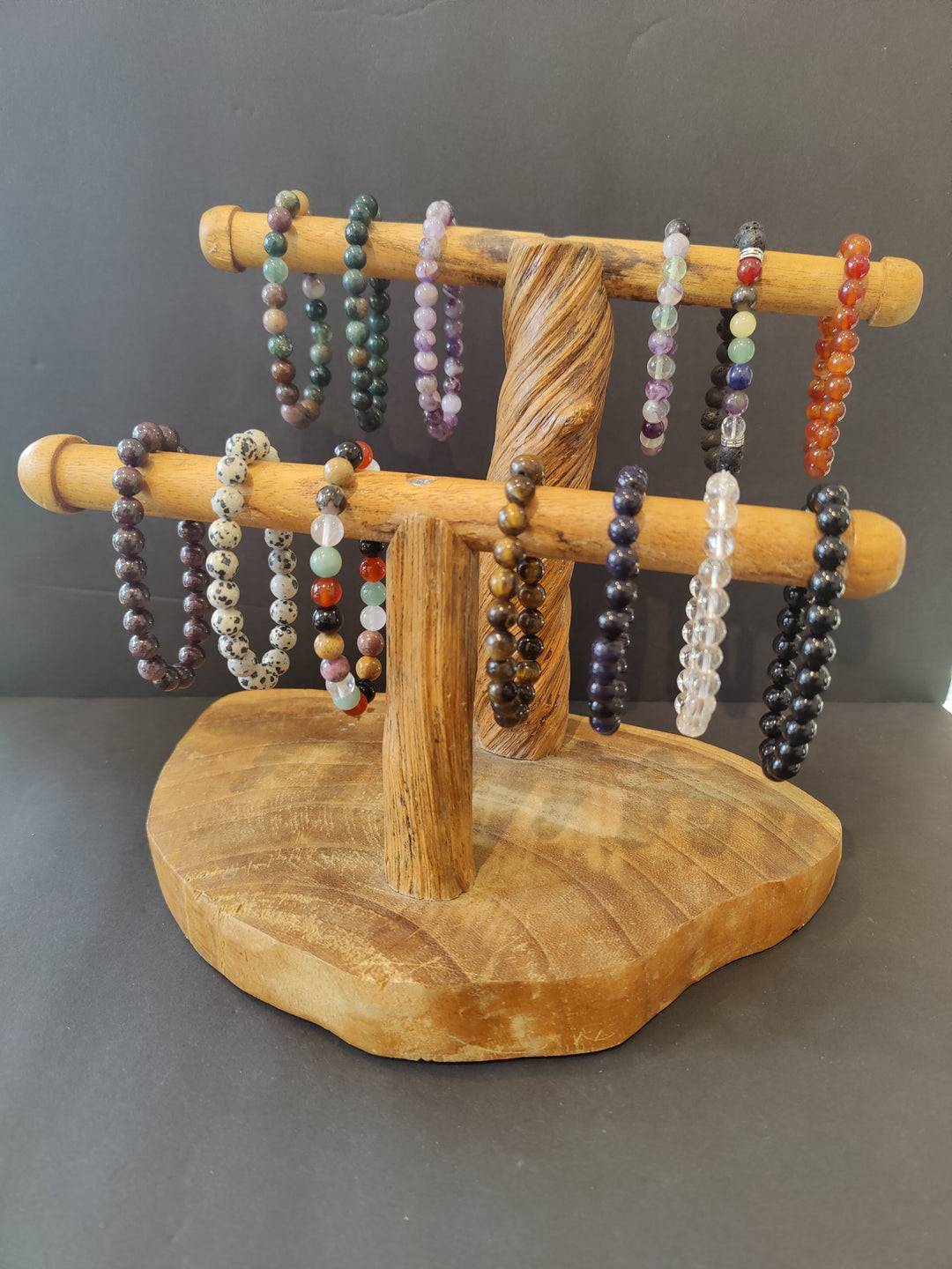 Beaded stone bracelets with mixed-color round beads on a wooden display stand