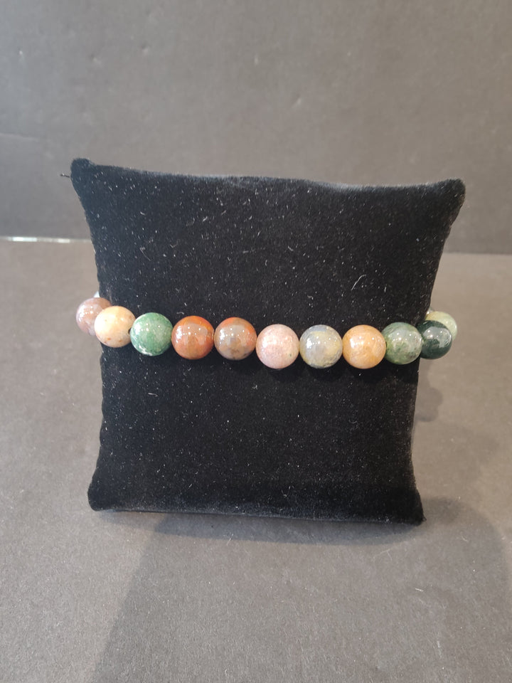 Beaded stone bracelet with pastel round beads on a dark jewelry display