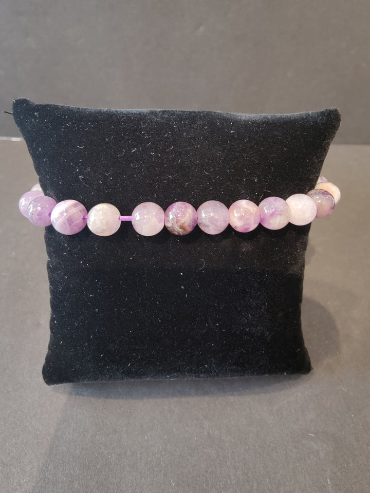 Beaded stone bracelet with pink and lavender round beads on a dark jewelry display