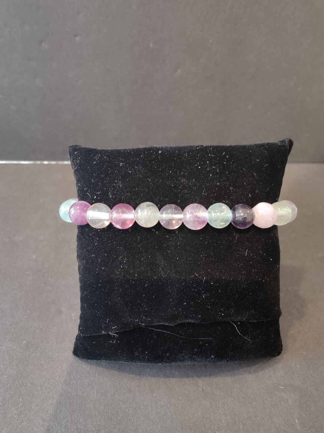 Beaded stone bracelet with pastel rainbow round beads on a dark jewelry display