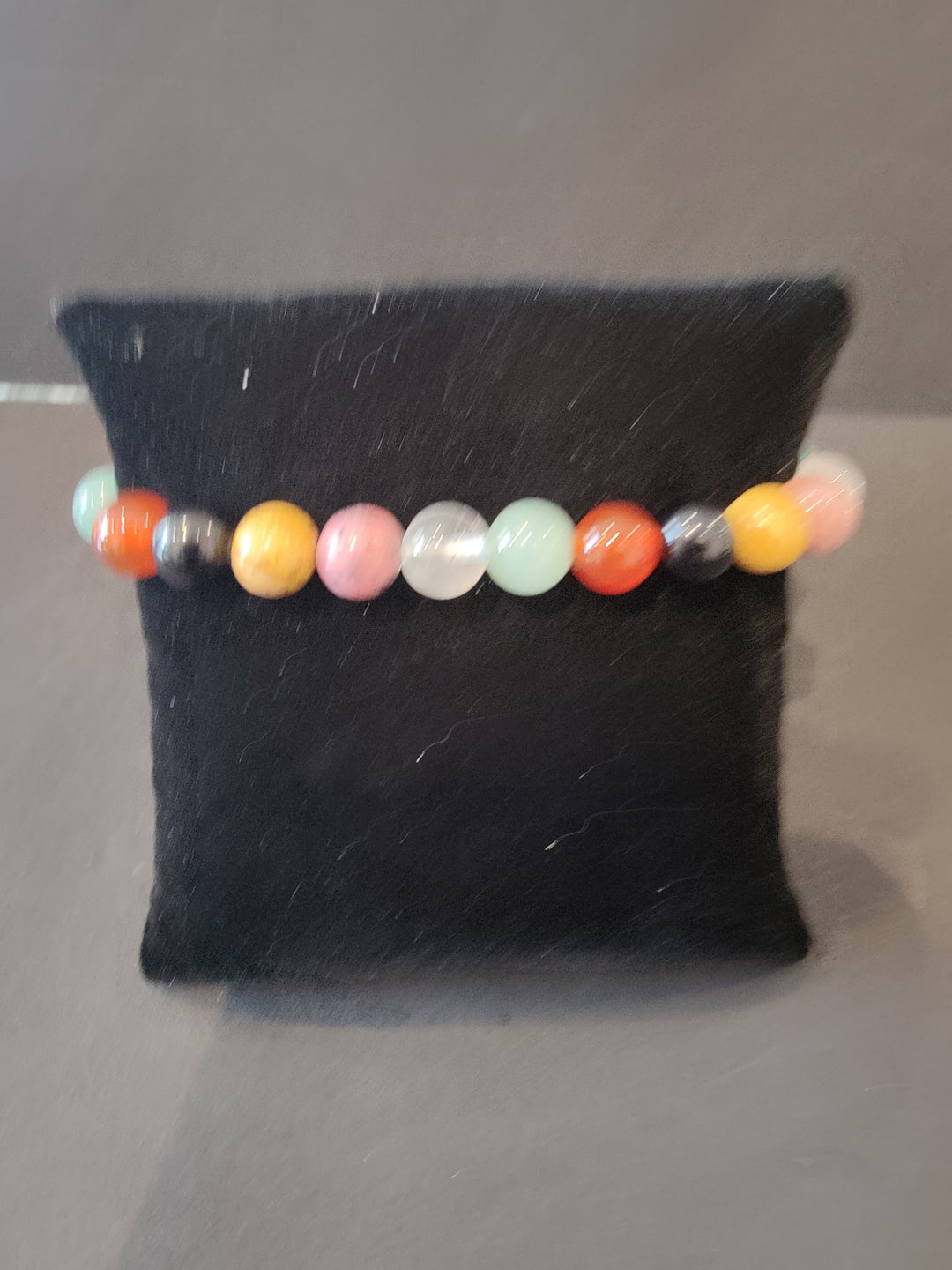 Beaded stone bracelet with multicolor round beads on a dark jewelry display