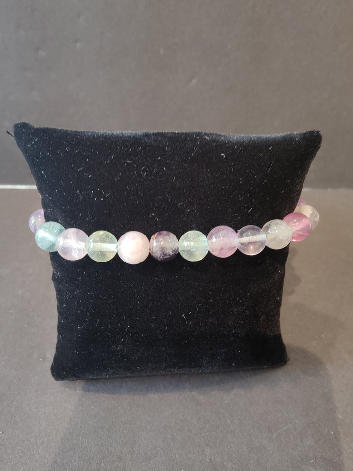 Beaded stone bracelet with pale pink, blue, and cream round beads on a dark display